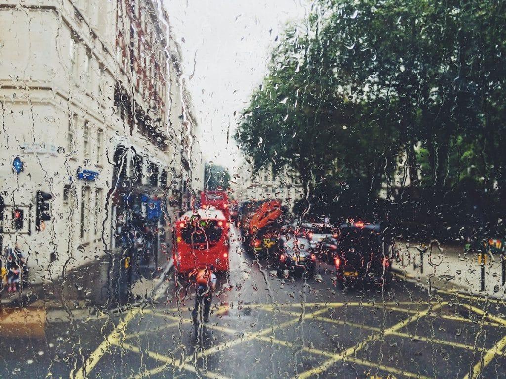 A person dressed in red cycles through the rain in London.