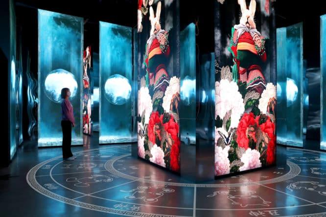 A woman looking at huge screens at the Delight London exhibition of Korean art